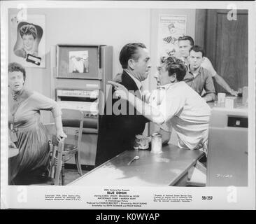 Ein Film noch Szene aus 'Blue Jeans' (1959 Twentieth Century Fox Film), in dem ein reifer Mann im dunklen Anzug ein anderer Mann ziehen in weißen Hemd durch den Bund auf einen Zähler, während mehrere Menschen sieht in der Überraschung, 1959. Stockfoto