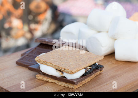 Smores Zutaten an einem Strand mit Lagerfeuer mit Schokolade, Eibisch, und Graham Cracker mit Raum für Kopie Stockfoto