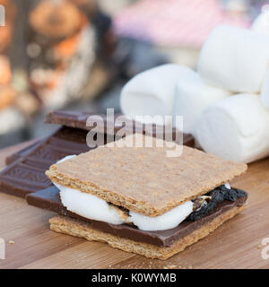 Smores Zutaten an einem Strand mit Lagerfeuer mit Schokolade, Eibisch, und Graham Cracker mit Raum für Kopie Stockfoto