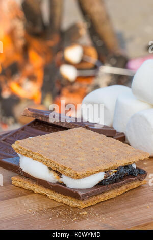 Smores Zutaten an einem Strand mit Lagerfeuer mit Schokolade, Eibisch, und Graham Cracker mit Raum für Kopie Stockfoto