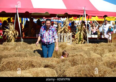 Mutter und Kind Tochter gehen durch einen Heu Kaution Labyrinth. Stockfoto