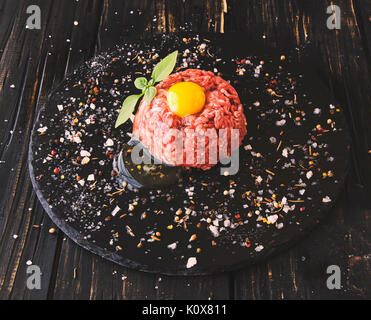 Rohes Hackfleisch, Gemüse mit Salz und Gewürzen, auf einem schwarzen Hintergrund, selektiver Fokus, Platz für Text Stockfoto