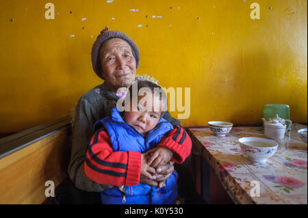 Tibetische Großmutter und Enkel in Rebkhong. Tibetischen Plateau (Tongren, China) Stockfoto
