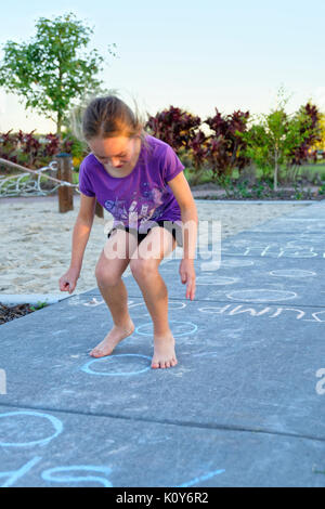 Kinder spielen im Park mit hopse und folgenden Kreidezeichnungen auf dem Bürgersteig Stockfoto