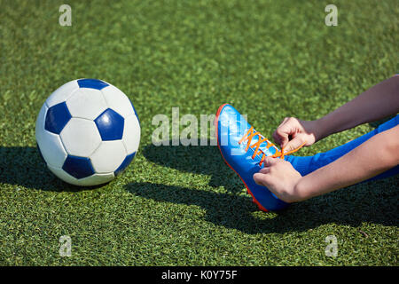 Jungen Fußball Fußball Binden der Schnürsenkel auf die Stiefel auf grünem Gras Stockfoto