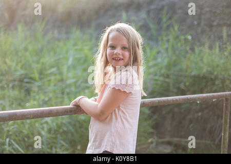 Kleine Mädchen stehen auf einer Brücke von einem Fluss Stockfoto