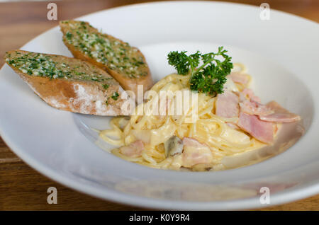 Spaghetti Carbonara mit Schinken und Champignons mit Knoblauch Brot. Stockfoto