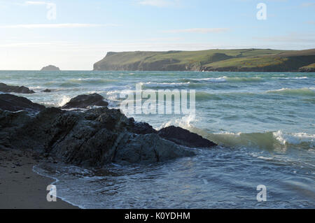 Wellen und die Brandung gegen die Felsen zerschmettert auf dem sandigen Strand von Surfers polzeath in North Cornwall. grosse Wellen in einer stürmischen Wetter Tag auf Cornwall Stockfoto