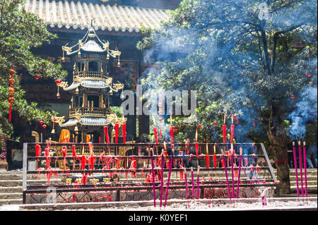 Kerzen und Räucherstäbchen brennen in einem buddhistischen Tempel Stockfoto