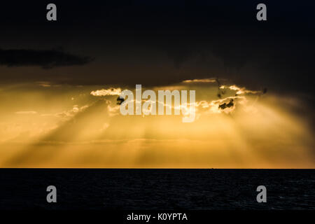 Gelber Sonnenuntergang mit Piercing Licht Strahlen durch die Wolken. Stockfoto