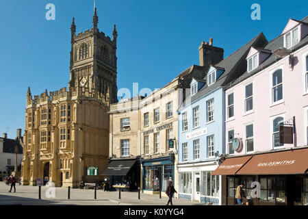 Die Menschen in der Frühlingssonne im vor kurzem regeneriert historischen Marktplatz von der Abteikirche in Cirencester Gloucestershire, Vereinigtes Königreich. Stockfoto