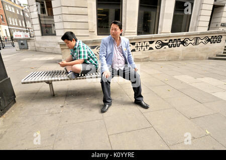 London, England, Grossbritannien. Asiatischer Mann und sein Sohn mit einem Mobiltelefon Stockfoto