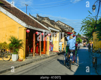 Hoi An, Vietnam - 28.November 2015. Menschen mit Cyclo auf der Main Street in der Altstadt von Hoi An, Vietnam. Hoi An ist Vietnam die meisten atmosphärischen und sehr schön Stockfoto