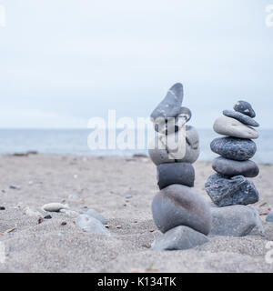 Monochrom, ruhigen, blauen gestapelte Steine auf einem Kalifornischen Strand als Symbol für Frieden, Gleichgewicht, Meditation und Achtsamkeit Stockfoto