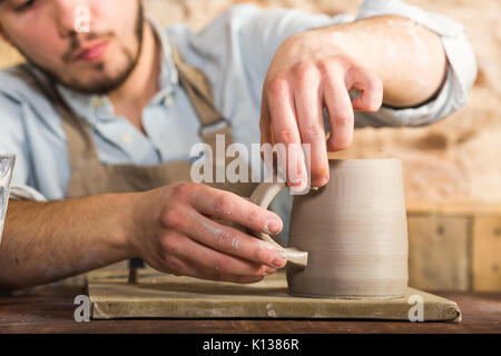 Potter, Steingut, Keramik Kunst Konzept - handwerkliche Hände die Tasse und den Griff der Rohstoff Ton gemacht, Master Finger Arbeiten mit Ton, Stockfoto