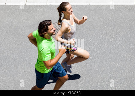 Schöner Mann und schöne Frau joggen zusammen auf der Straße an einem sonnigen Tag Stockfoto