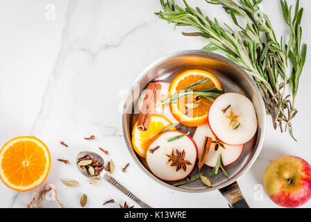Traditionelle Winter und Weihnachten Getränke, Zutaten für Glühwein, heiße Getränke mit Zitrusfrüchten, Apple und Gewürze in Aluminium Kasserolle auf weißem Marmor t Stockfoto
