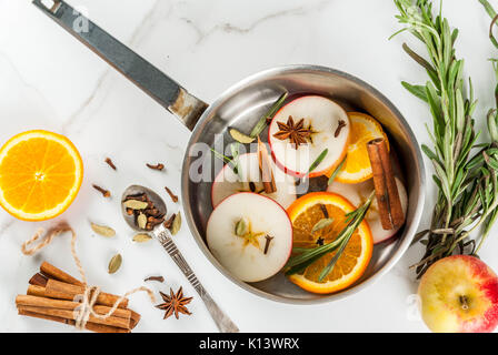 Traditionelle Winter und Weihnachten Getränke, Zutaten für Glühwein, heiße Getränke mit Zitrusfrüchten, Apple und Gewürze in Aluminium Kasserolle auf weißem Marmor t Stockfoto