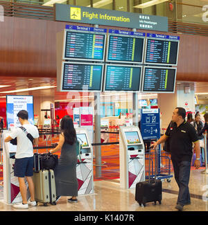 Singapur - Januar 13, 2017: Passagiere am Check-in-Automaten in der Nähe der Information Board in Changi Airport. Changi Airport dient mehr als 100 Airlines Stockfoto