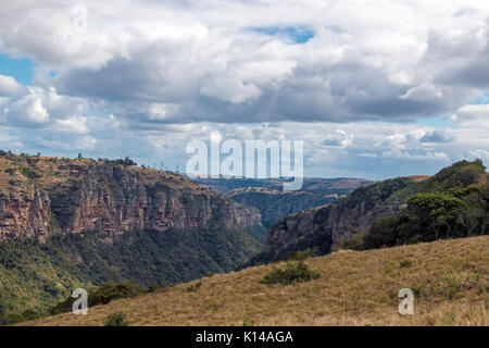 Blick vom Lake Eland Game Reserve von Trockenrasen Klippen Berge und Täler gegen den blauen bewölkten Himmel Landschaft bei Oribi Gorge in Südafrika Stockfoto