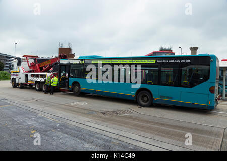 Ein nach unten gebrochen-Bus bereit, durch eine große mächtige Pannenhilfe Lkw abgeschleppt werden. Am zentralen Busbahnhof des Flughafens Heathrow, London. Großbritannien (89) Stockfoto