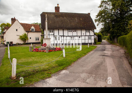 Kriegerdenkmal auf dem Dorfplatz mit schwarzen und weißen Fachwerkhaus mit Reetdach in Dorchester auf Themse Oxfordshire halbieren Stockfoto