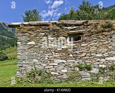 Verfallene Scheune mit Steinmauern und Fenster vor einem blauen Himmel in den österreichischen Alpen Stockfoto