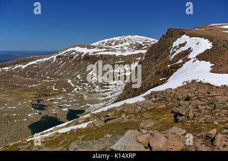 Auf dem Gipfel des Cairn Gorm mit Tal, steilen Hängen, Steine, Schnee, Seen unter Stockfoto