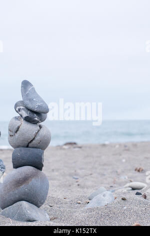 Monochrom, ruhigen, blauen gestapelte Steine auf einem Kalifornischen Strand als Symbol für Frieden, Gleichgewicht, Meditation und Achtsamkeit Stockfoto