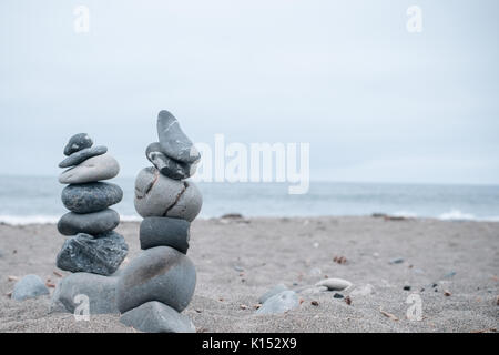 Monochrom, ruhigen, blauen gestapelte Steine auf einem Kalifornischen Strand als Symbol für Frieden, Gleichgewicht, Meditation und Achtsamkeit Stockfoto