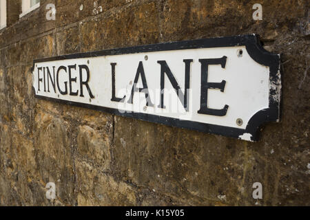 Alte Metall lokale Behörde Finger Lane Street Typenschild lage Zeichen mit schwarzem Text auf weißem Hintergrund montiert auf Steinmauer in Sherborne, Dorset UK Stockfoto