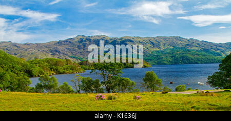 Panoramablick auf die ruhige, blaue Wasser des Loch Morar gesäumt mit zerklüfteten Bergen unter blauem Himmel in Schottland Stockfoto