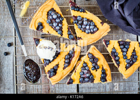 Stücke von hausgemachten öffnen Blueberry Pie mit Vanilleeis auf einer hölzernen Hintergrund, Ansicht von oben, rustikalen Stil. Stockfoto