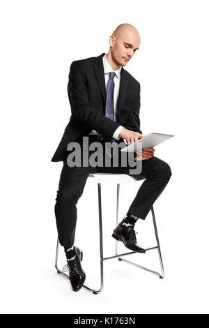 Konzentriert man Arbeiten an Tablet. Seitenansicht des jungen Mannes auf weißem Hintergrund. Stockfoto