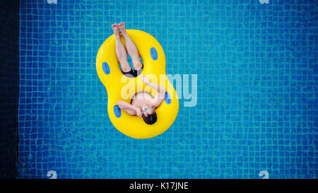 Ansicht von oben, ein Mann entspannt auf gelb Pool schwimmen, am Pool im Sommer Stockfoto