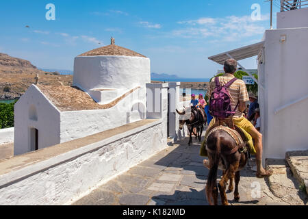 Touristen, der auf einem Esel vorbei an der Kapelle des heiligen Georg Pahimahiotis. Lindos, Insel Rhodos, Griechenland Stockfoto