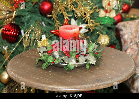 Dekorative Weihnachten Kerze auf Holztisch und Christbaumschmuck in der Rückseite Stockfoto