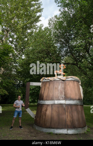 Der Kerl hat einen riesigen hölzernen Krug mit Bier in der City Park. Stockfoto