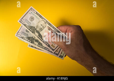 Die Hand eines Mannes hält aus Dollar. Hand und Geld auf einem gelben Hintergrund. Stockfoto
