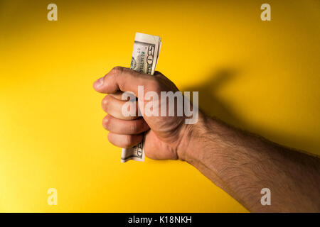 Die Hand eines Mannes hält aus Dollar. Hand und Geld auf einem gelben Hintergrund. Der Mangel an Geld. Familie Haushalt. Stockfoto