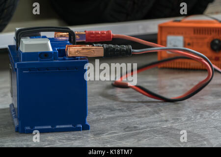 Aufladen der Autobatterie auf einer hölzernen Hintergrund. Stockfoto