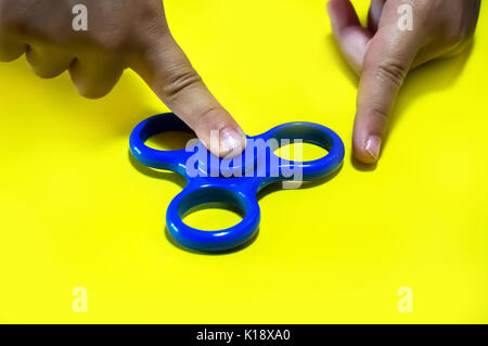 Leistungsstarke Spinner, Twister für Hände Unterhaltung rotierende Spielzeug. die Hände des Kindes Spinner auf gelbem Hintergrund twist Stockfoto