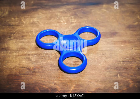 Blau zappeln Spinner auf Holztisch isoliert. Leistungsstarke Spinner, Spinner, Twister für Hände Unterhaltung rotierende Spielzeug Stockfoto