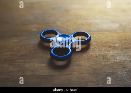 Blue spinner Holztisch Hintergrund. Leistungsstarke Spinner, Spinner, Twister für Hände Unterhaltung rotierende Spielzeug Stockfoto