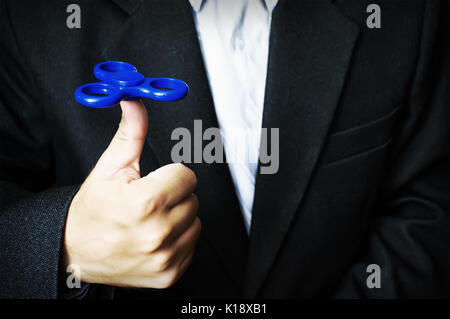 Blaue Straße Spinner in der Hand eines Mannes in einem Geschäft Jacke und ein weißes Hemd. Leistungsstarke Spinner, Twister für Hände Unterhaltung rotierende Spielzeug. Antistr Stockfoto