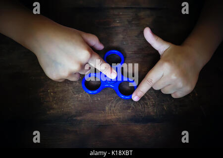 Leistungsstarke Spinner, Twister für Hände Unterhaltung rotierende Spielzeug. die Hände des Kindes Spinner auf einem Holztisch twist Stockfoto