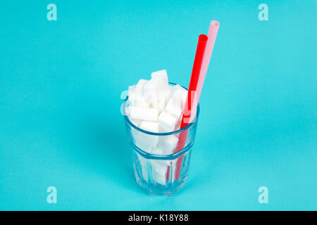 Ein klares Glas mit Zucker Würfel auf einem pop türkis Hintergrund gefüllt. Minimale Farbe still life Fotografie Stockfoto