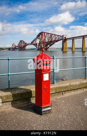 Red Royal Mail Post Box am Ufer des Firth-of-Forth mit der Forth Rail Bridge im Hintergrund in South Queensferry Edinburgh Stockfoto