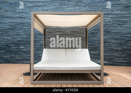 Holz- Liege Sonnenliege im Resort mit schwarzen Mauer Hintergrund. Stockfoto