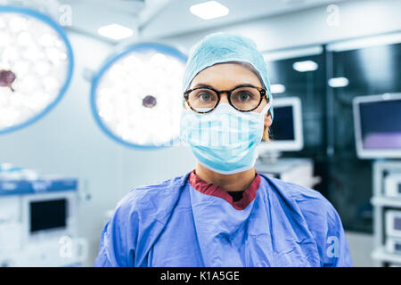 Close up Portrait von weiblichen Chirurg das Tragen von Mundschutz und Peelings in Betrieb Theater. Professionelle medizinische bereit für den Einsatz im Krankenhaus. Stockfoto